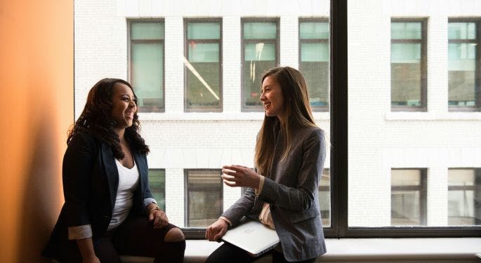 Two female coworkers talking in an office building.