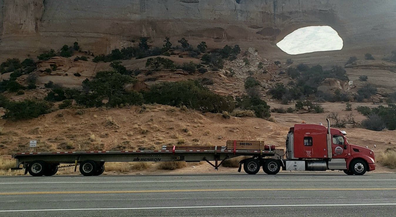 A commercial vehicle, a semi truck, is seen driving along the road, transporting goods with efficiency and power.