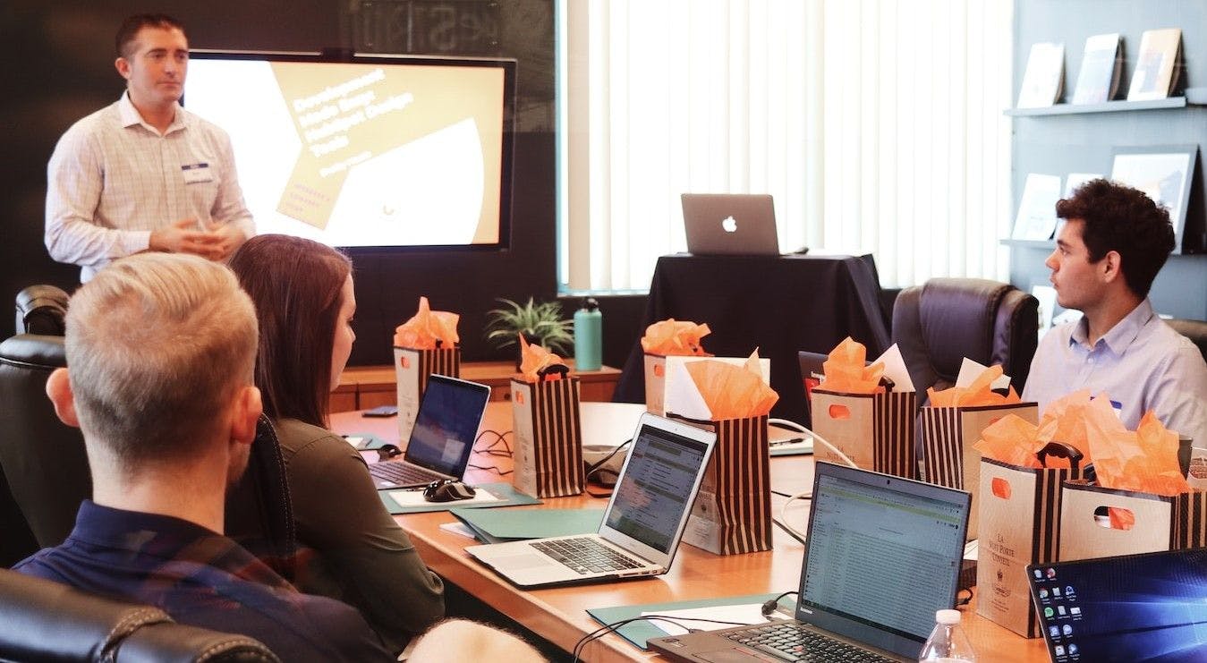 A gathering of individuals seated at a table, each engrossed in their own laptop, engaged in a collaborative work session.