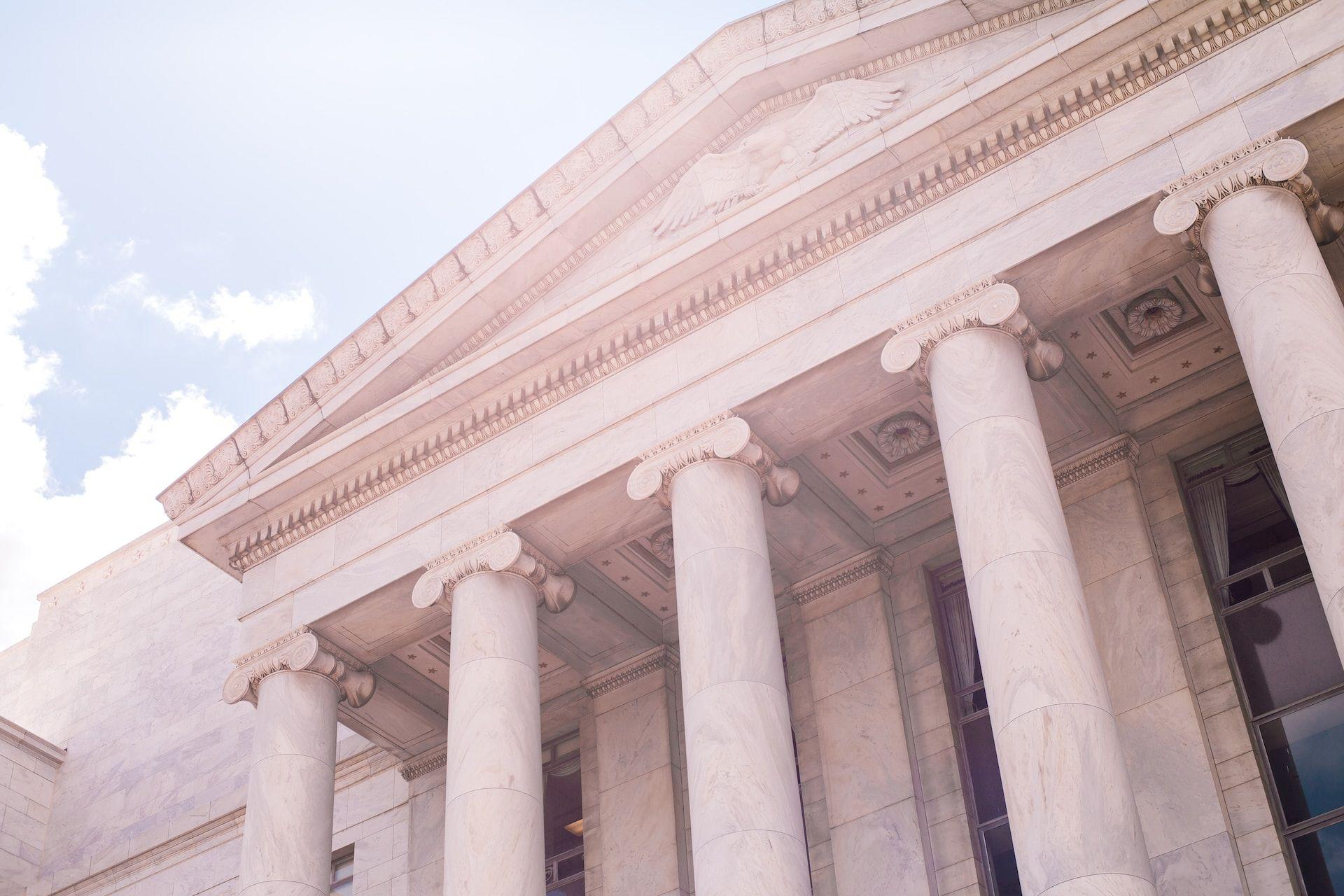 The image depicts the frontal view of a building adorned with elegant columns and pillars.