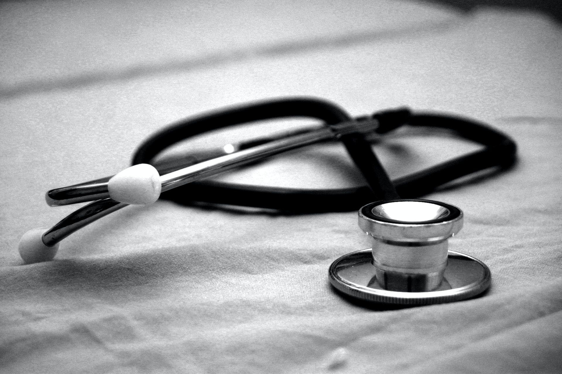 A stethoscope and pen neatly placed on a bed, ready for medical examination or note-taking.