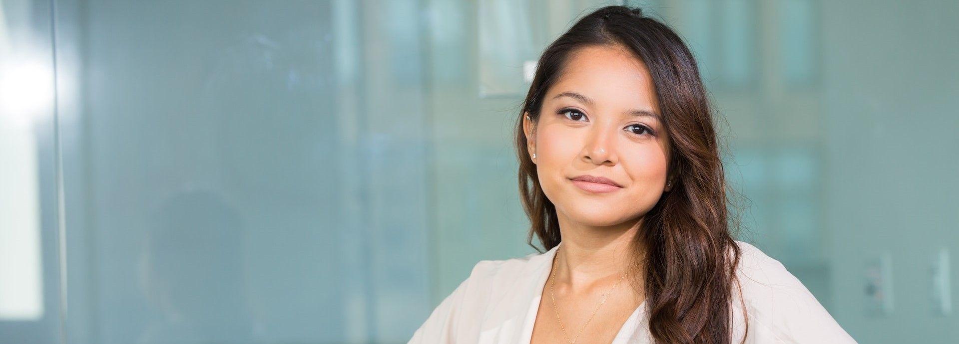  A woman wearing a white shirt is displaying a pleasant expression with a smile on her face.