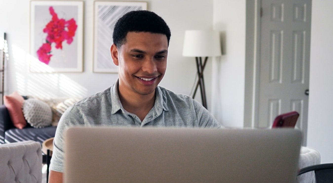 A male individual is seated at a desk, working on a computer.