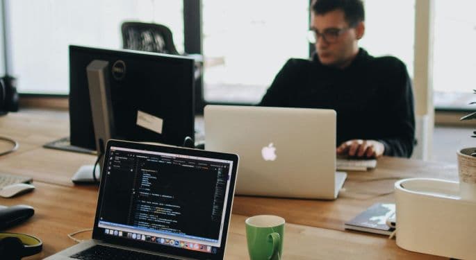 People working on laptops at a shared desk.
